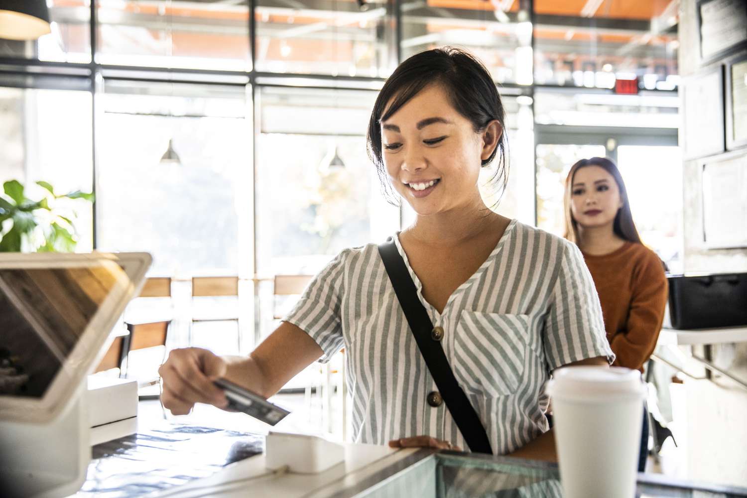 Woman using a credit card reader at a coffee shop counter