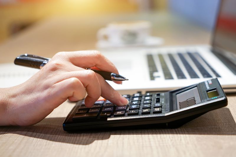 A woman hand working with calculator sitting at a desk.