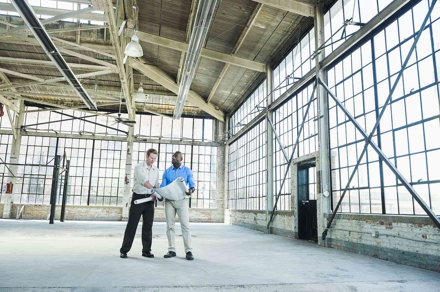 Businessmen reading blueprints in empty warehouse Real Estate Crowdfunding Sites