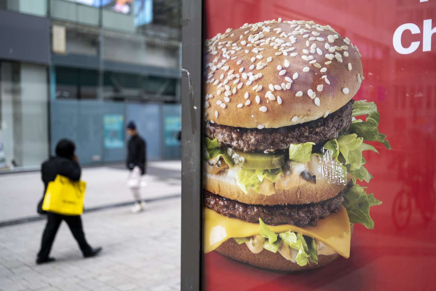 A McDonald's Big Mac is seen on an advertisement in the U.K. as people walk by