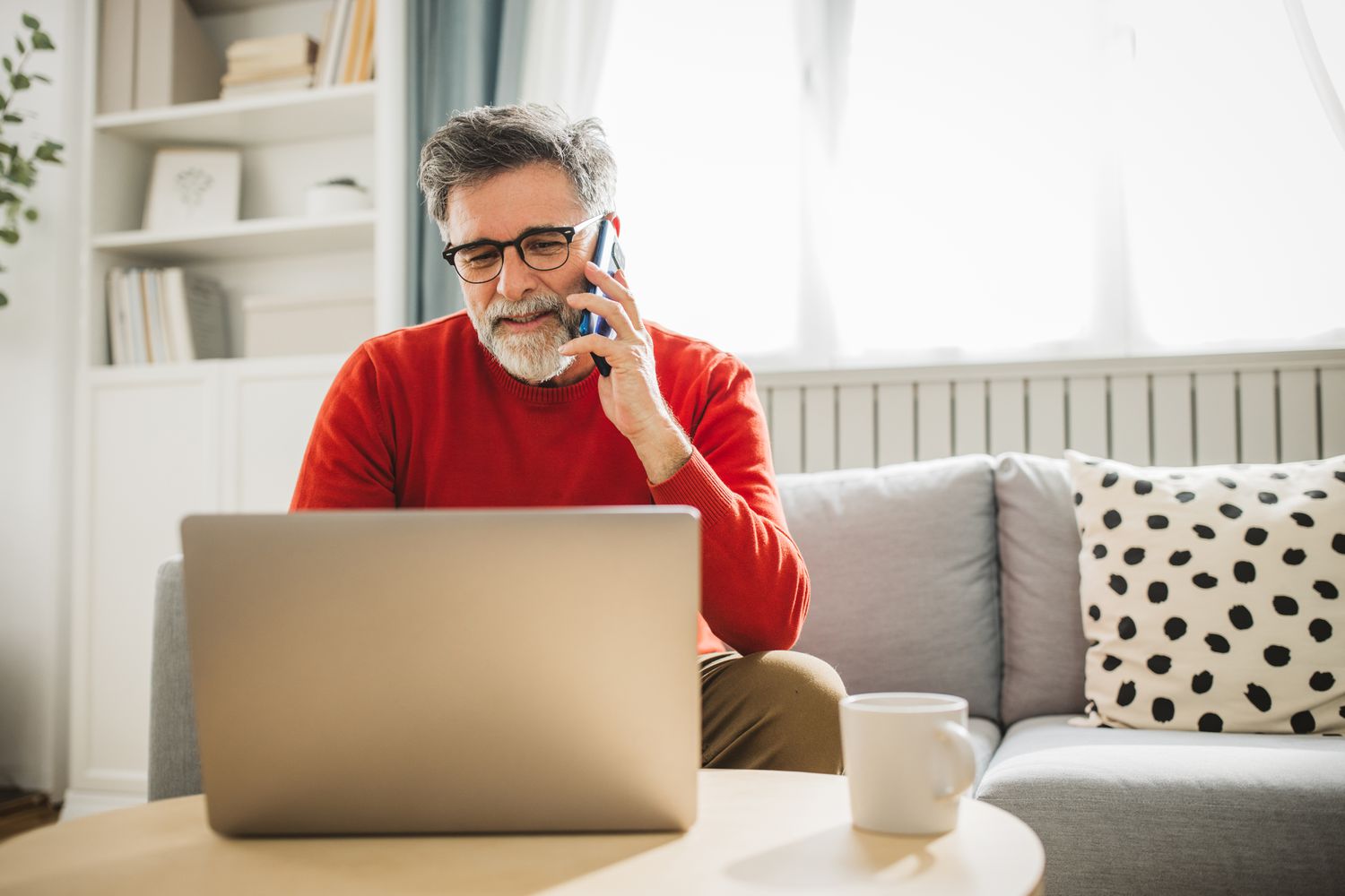 A man at a computer talking on the phone