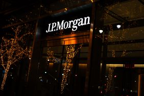 The J.P.Morgan sign is seen on the side of a building, as a tree with Christmas lights is seen outside.