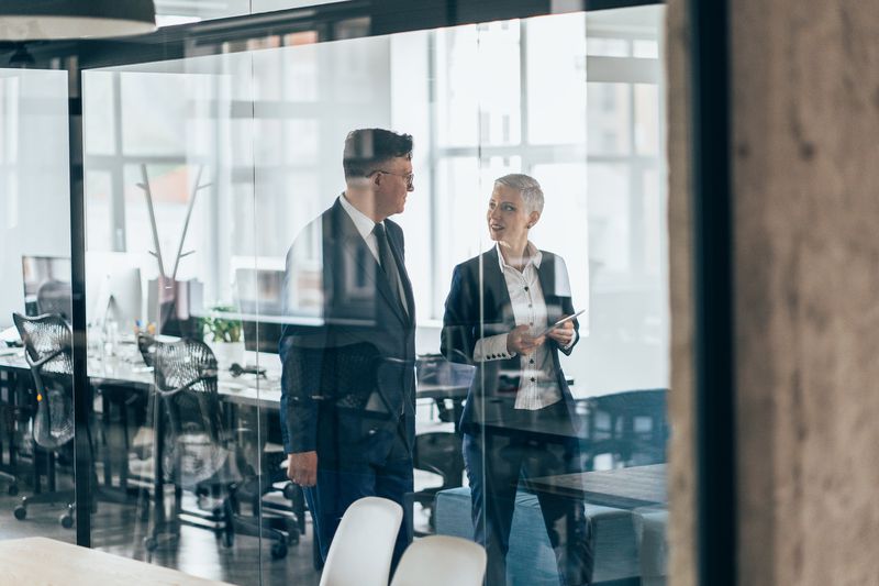 Business people walking and talking discussing ideas in the office.