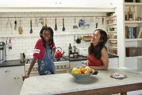 Two young adults have a conversation in a kitchen.