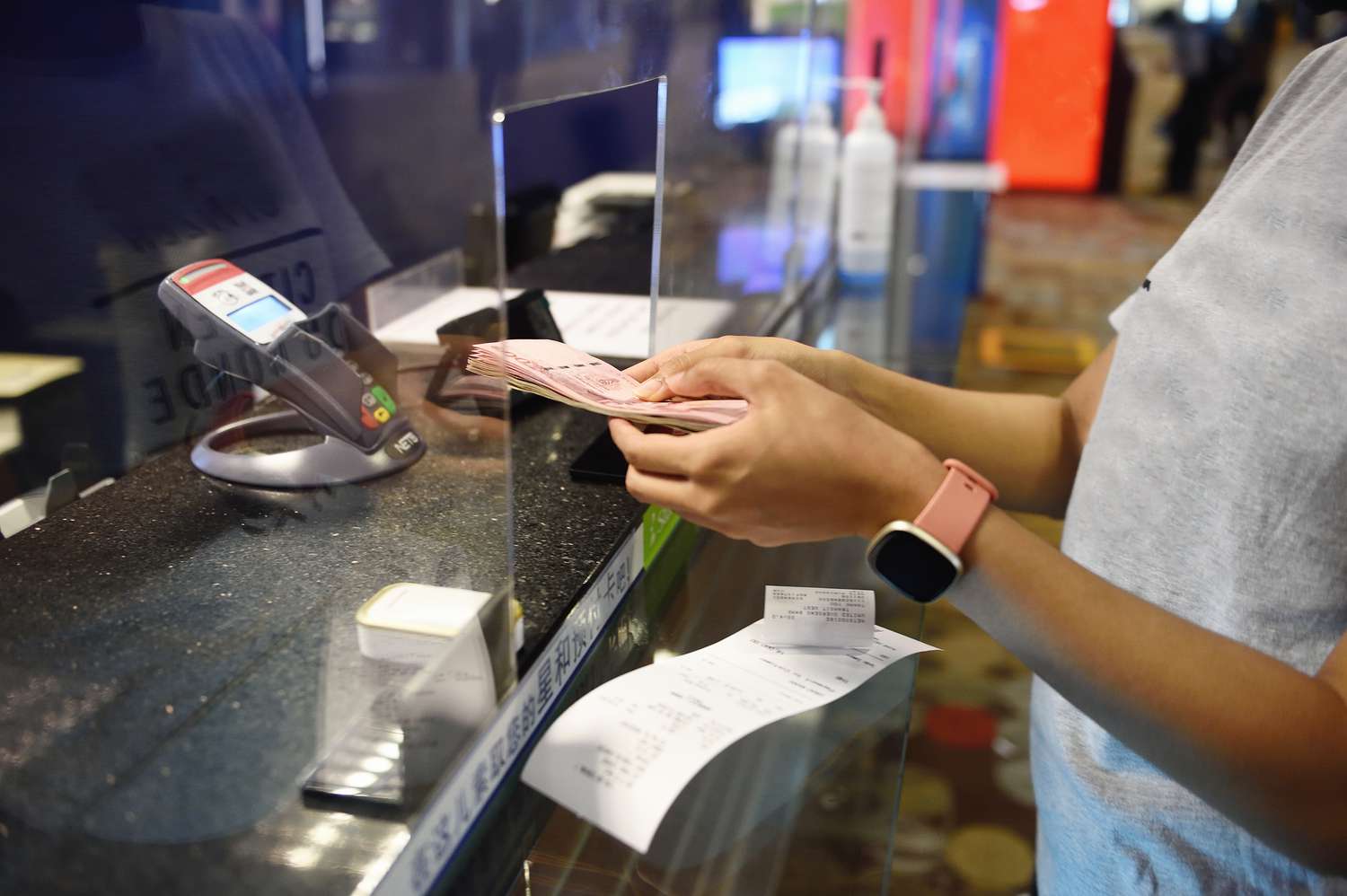 A person at a currency exchange handing over a small stack of bills.