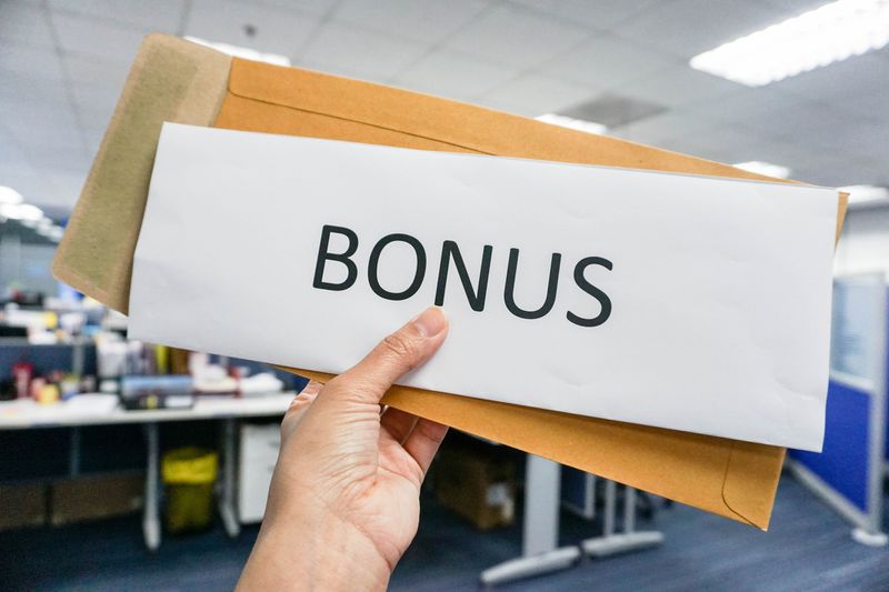 An envelope with paper that says "bonus" in a workplace