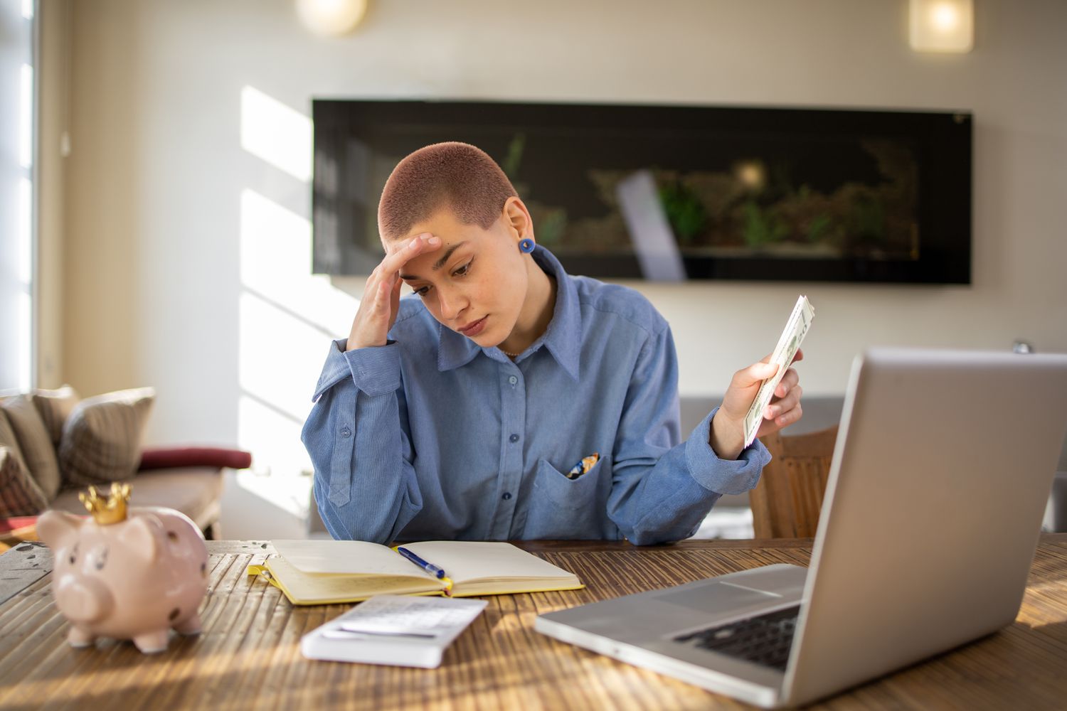 A woman shows stress as they calculate a loan payment while holding their salary statement