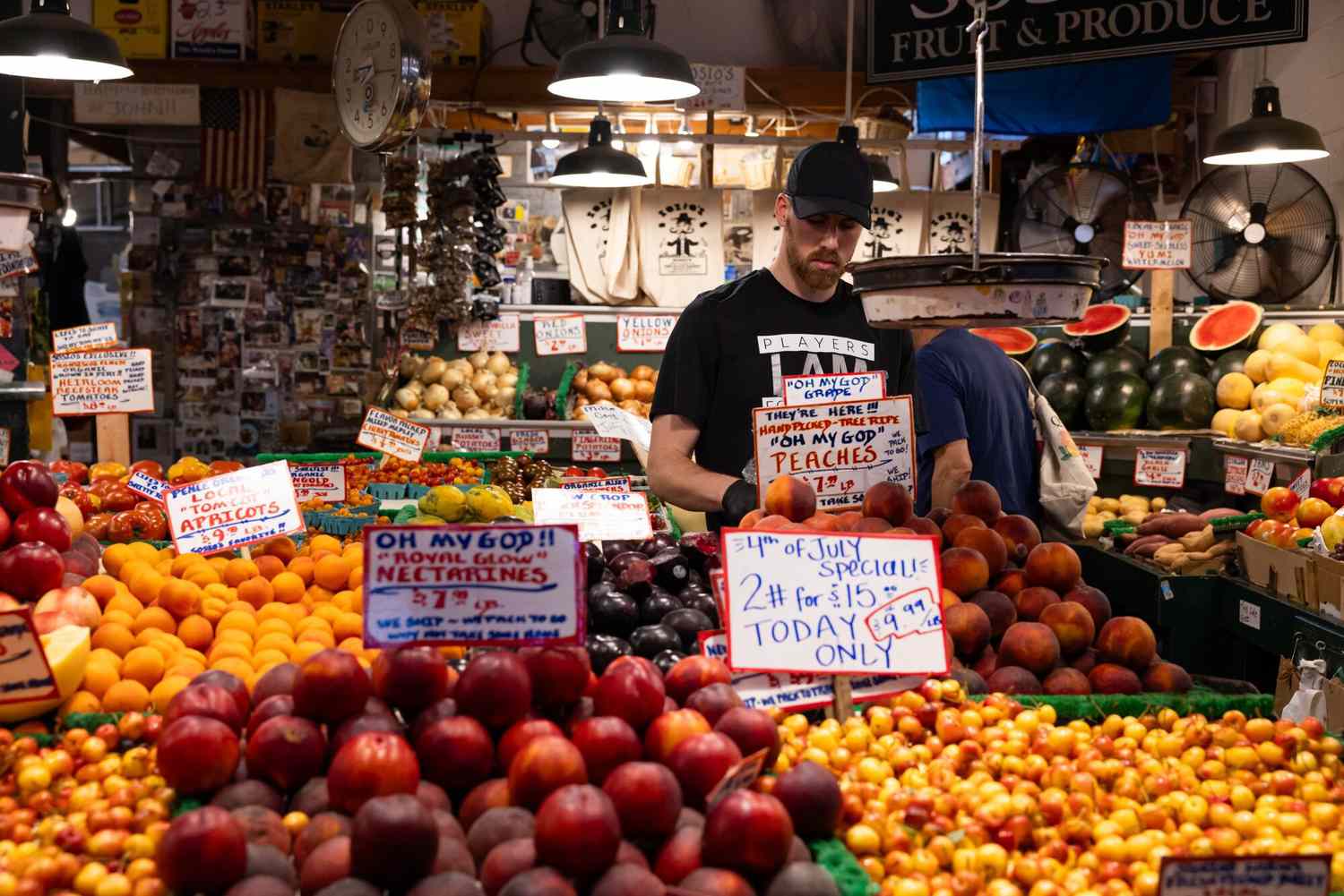 A worker arranges peaches at a fruit stand in the Pike Place Market in Seattle, Washington, US, on Thursday, July 4, 2024. 