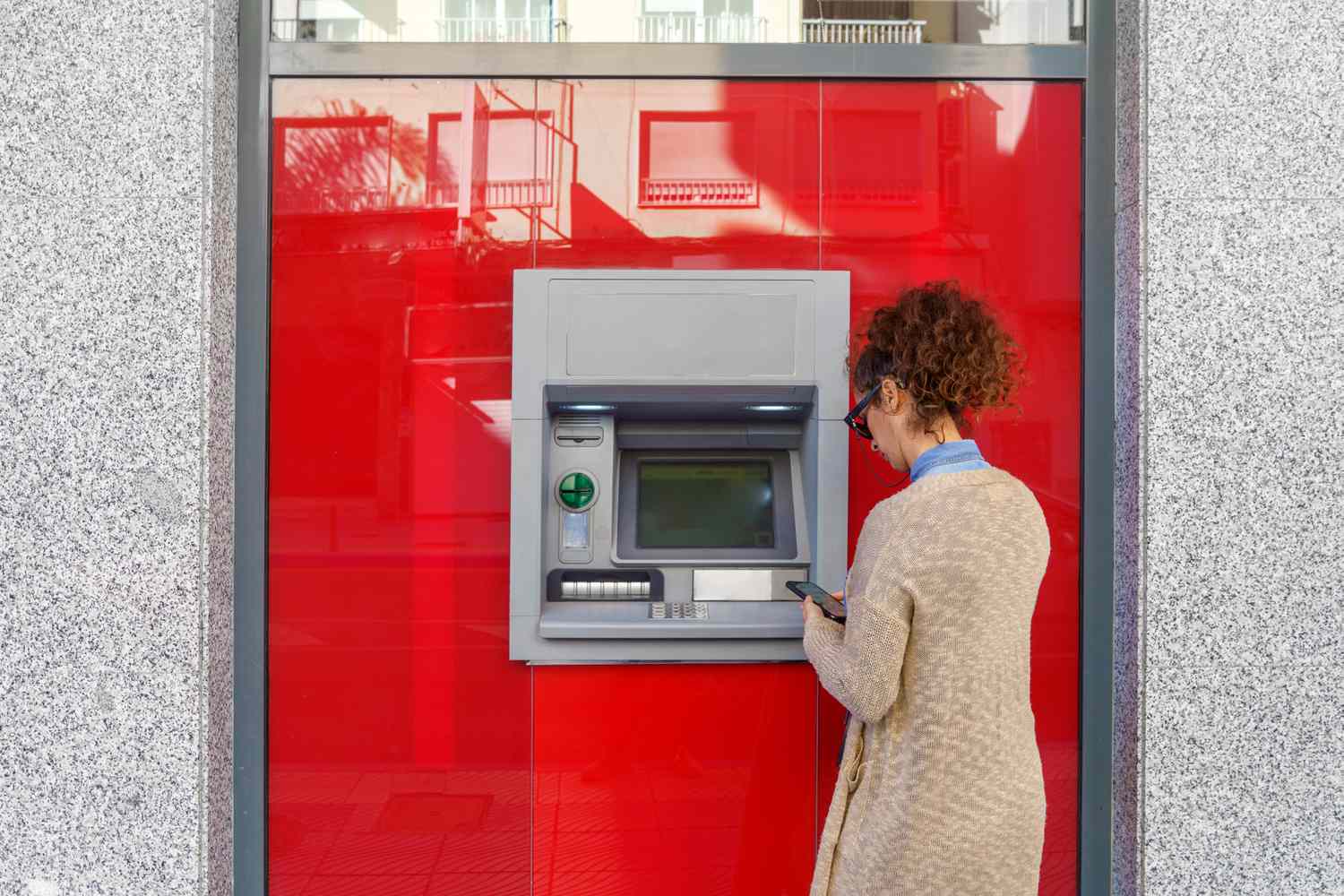 A person using the ATM of a zombie bank, which is still operating because of government's support.