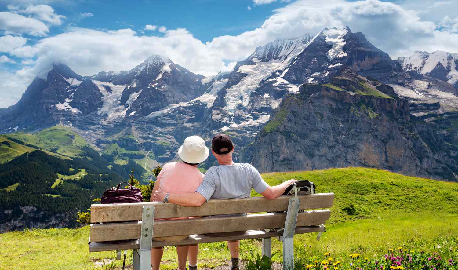 Senior couple enjoy view of Eiger and Jungfrau alps from a rest area for hikers on the mountain view trail in the Jungfrau region of the Swiss alps. 