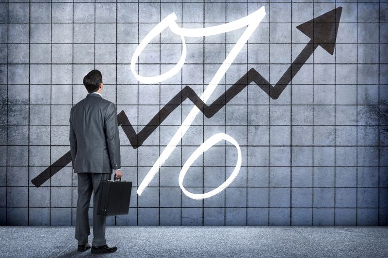 Businessman looking up at an arrow going up over a percent sign