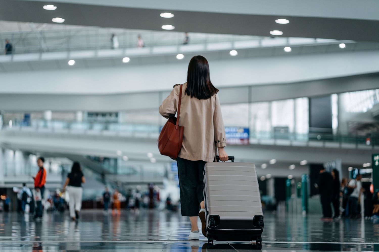 woman carrying suitcase walking in airport terminal