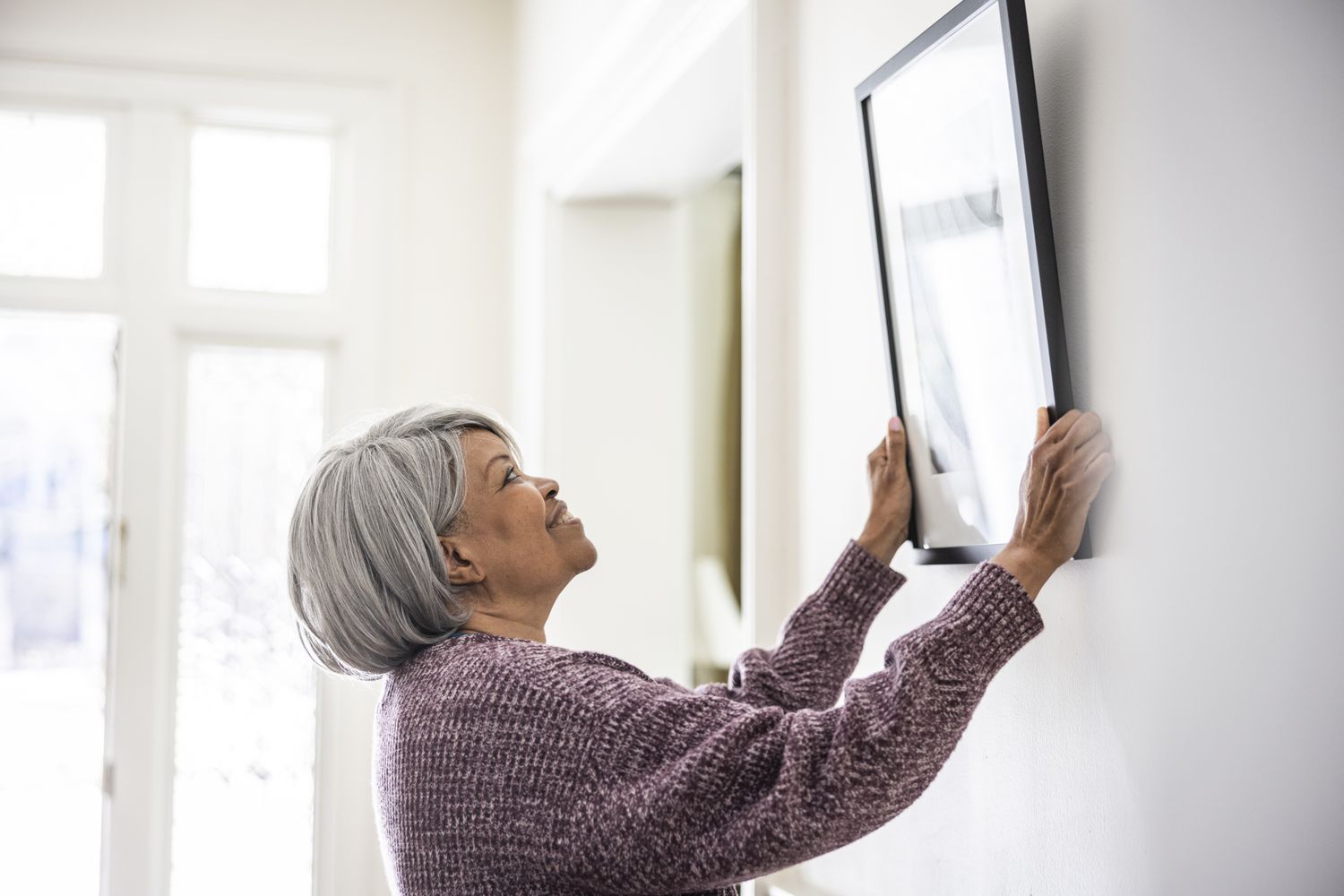 A woman hangs a photo on the wall