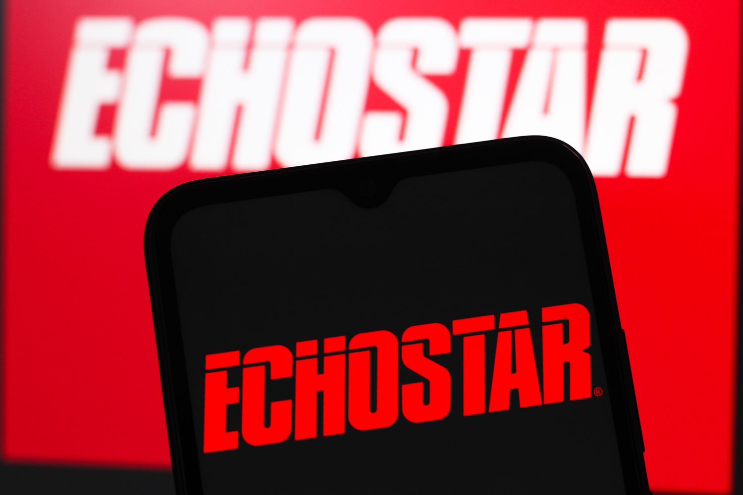 The red EchoStar logo is seen on a phone screen, with a larger red and white version in the background.