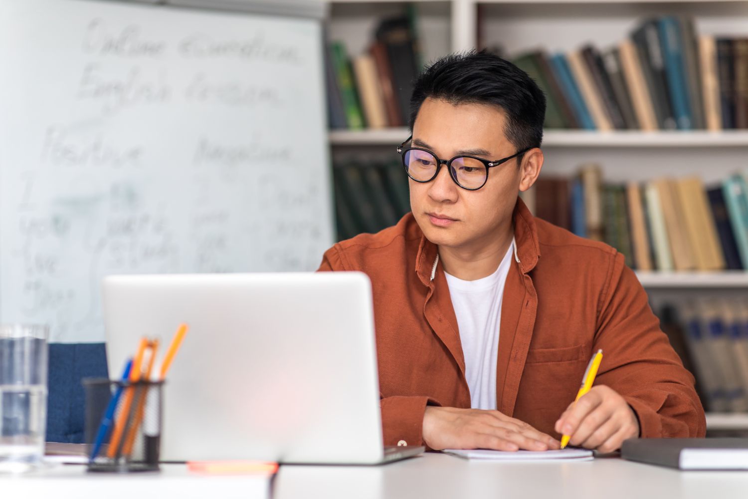 Asian man studying laptop and taking notes