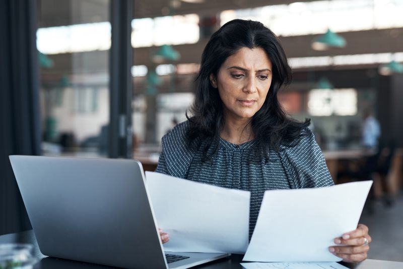 A woman reads documents in an office setting.