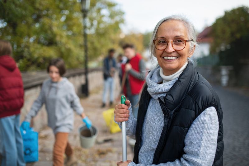 Senior woman volunteering to help clean street on a fall day.