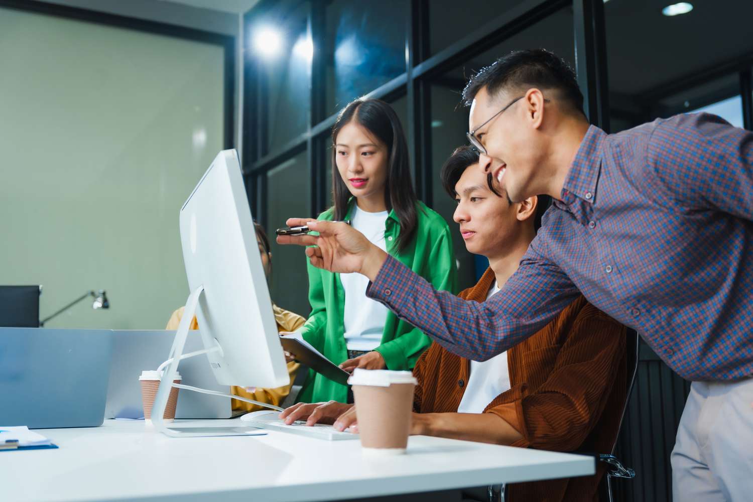 Three young people looking at something on a monitor.