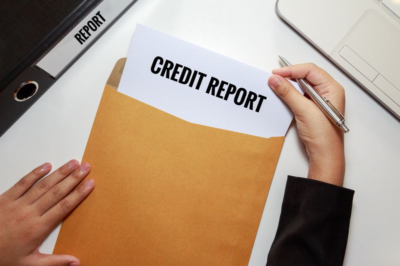 Cropped hands Removing credit report from envelope at table.