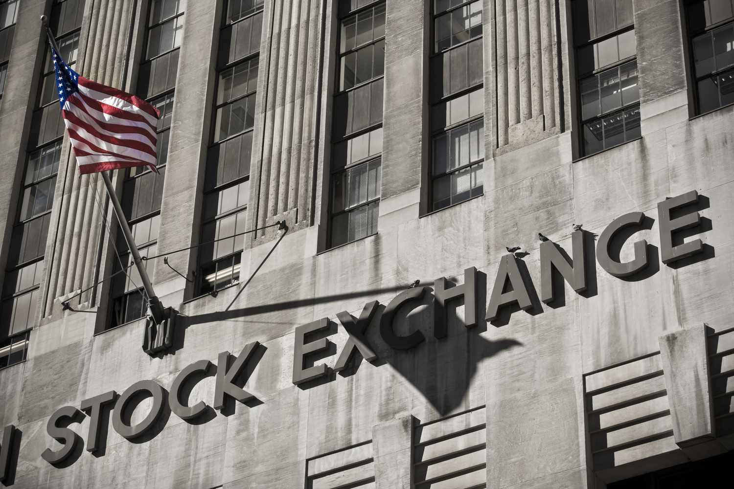 Close up view of the New York Stock Exchange building and an American flag.