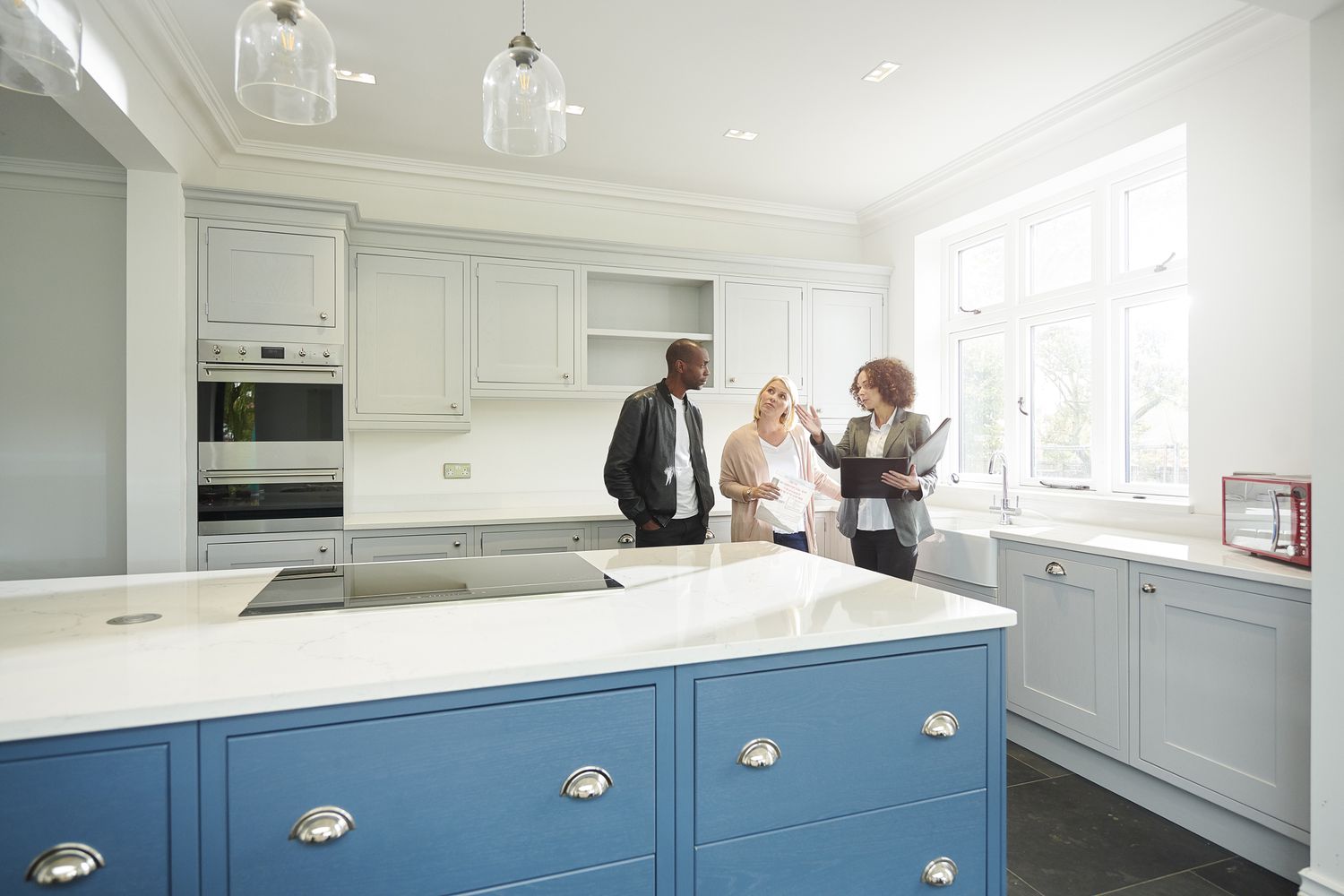 A man and a woman stand with female real estate agent in a kitchen of a house that is for sale