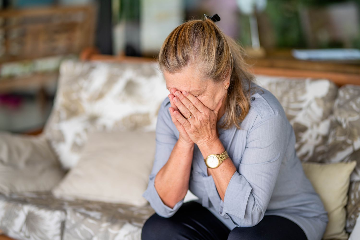 Woman on couch with her head in her hands