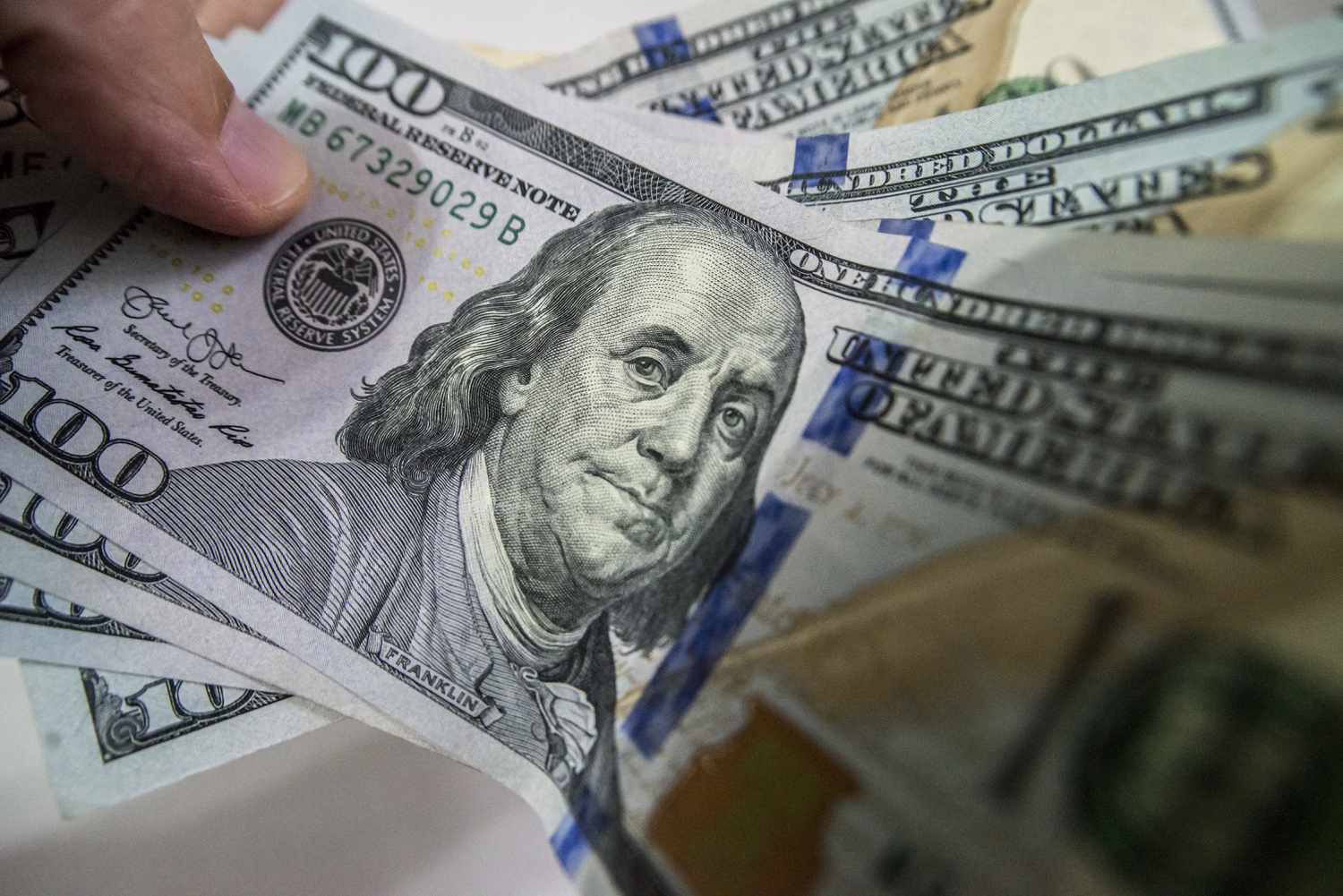 Hundred dollar bills held by a person. 