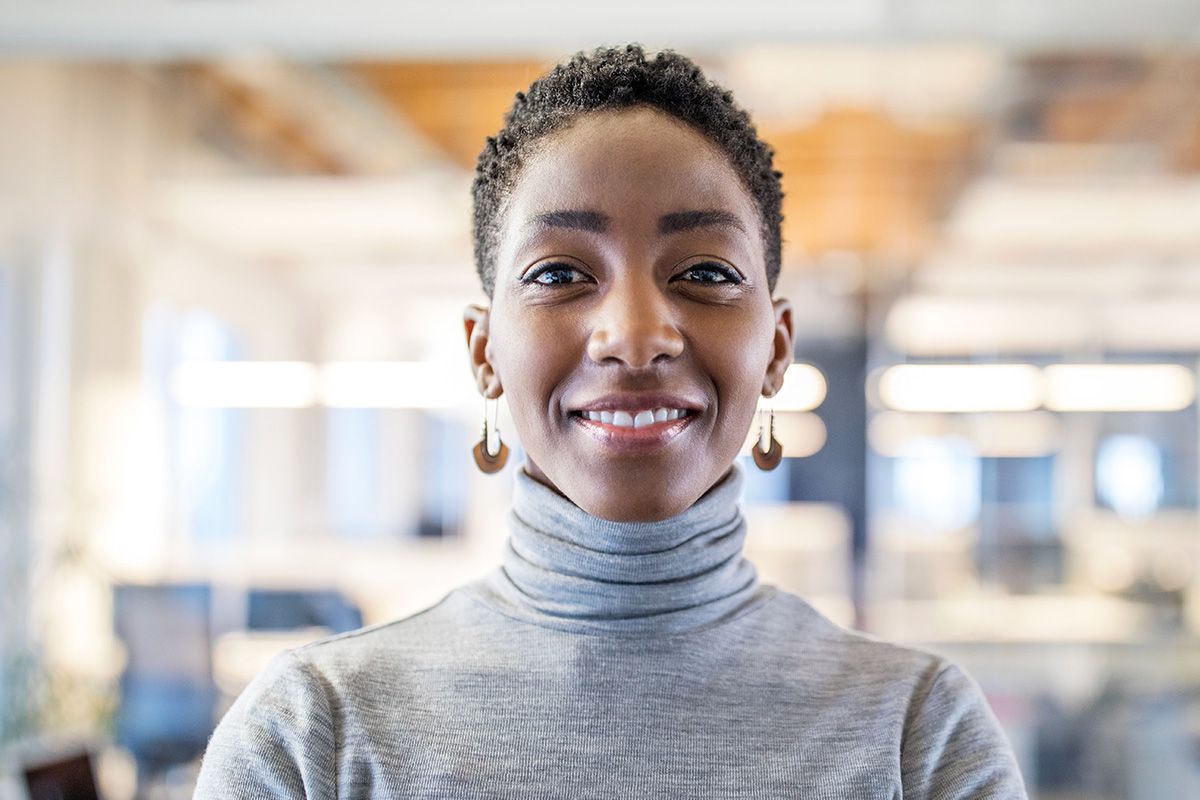 Woman smiling in office wearing turtleneck