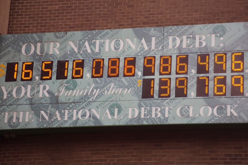 A digital national debt clock display board shows a string of digits below the words "Our National Debt".