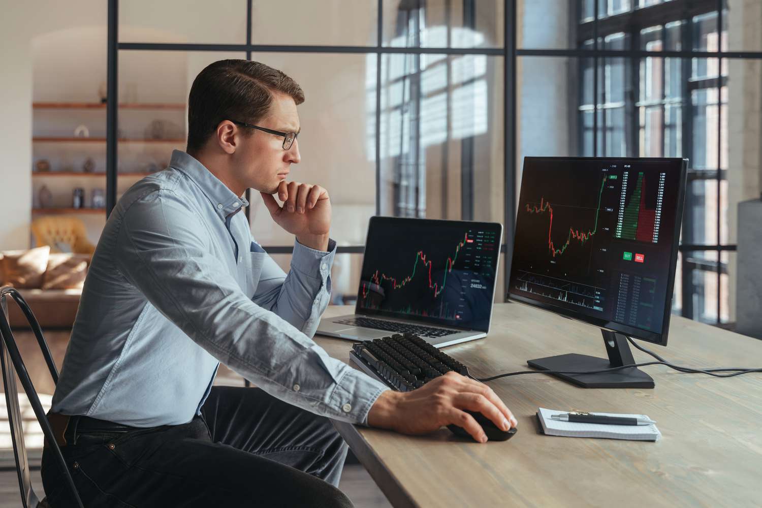 A trader sits at a desk using a computer to view technically weak market data for a stock they follow.