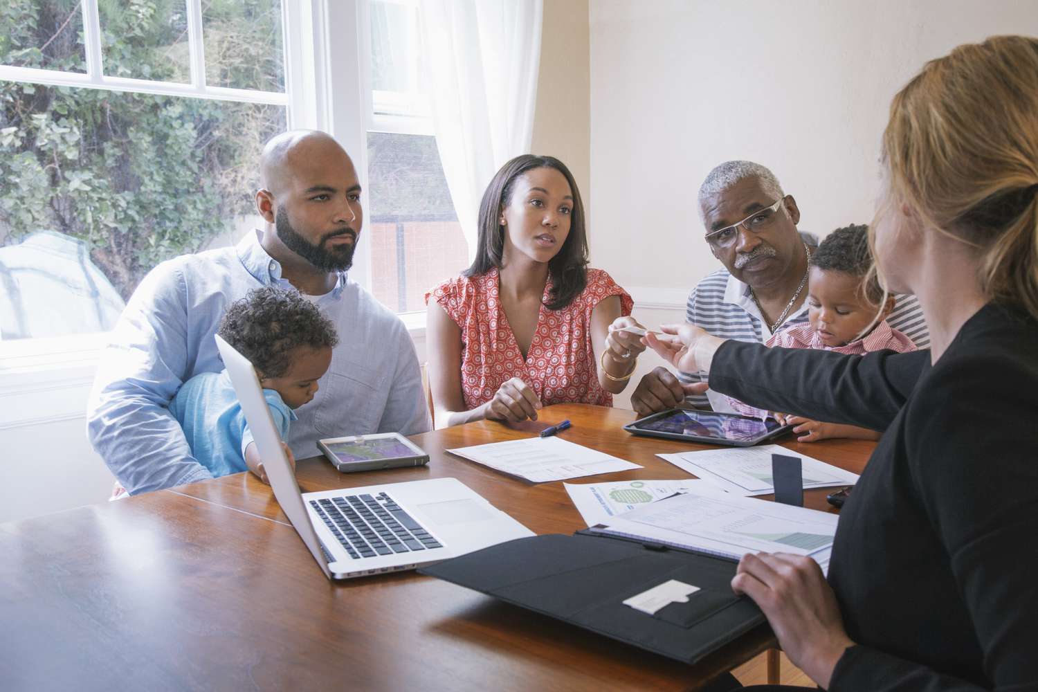 A lawyer works with a family where the father is signing over a house deed to their daughter and son-in-law.