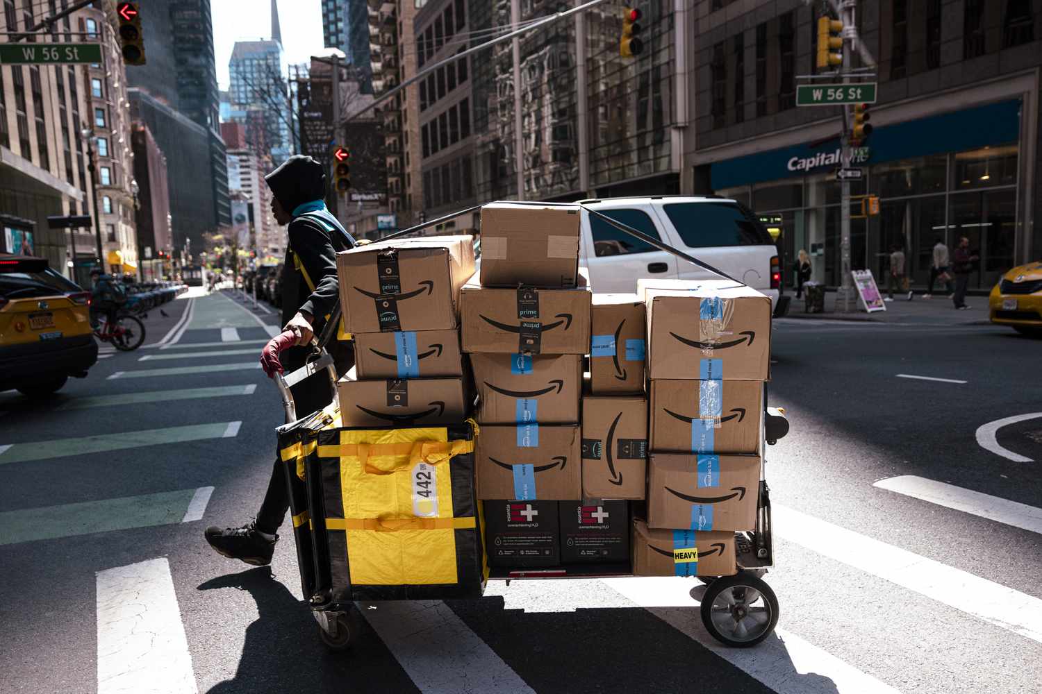 A worker pulls a delivery cart with Amazon packages