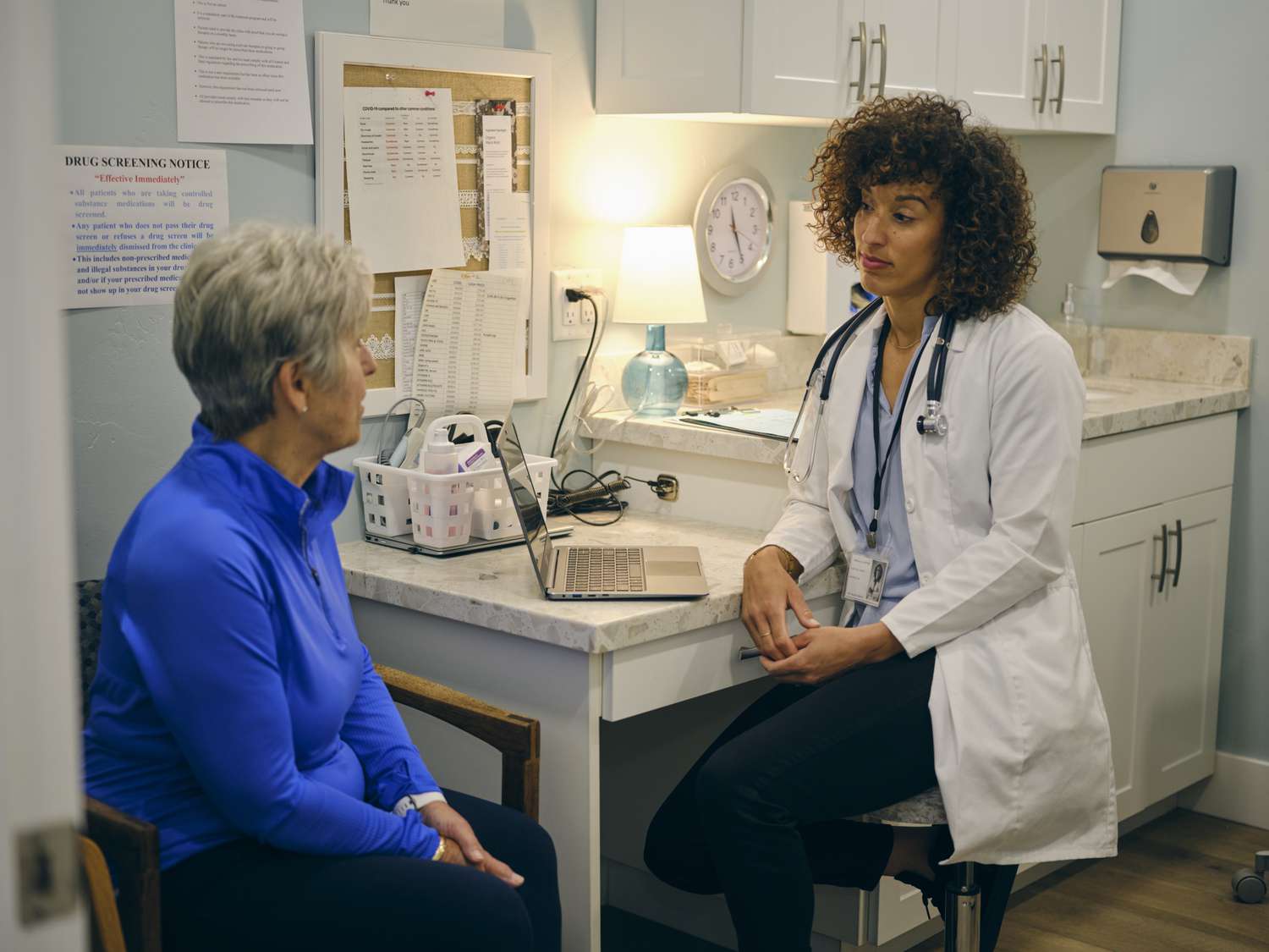 Female doctor talks to older female patient in an exam room