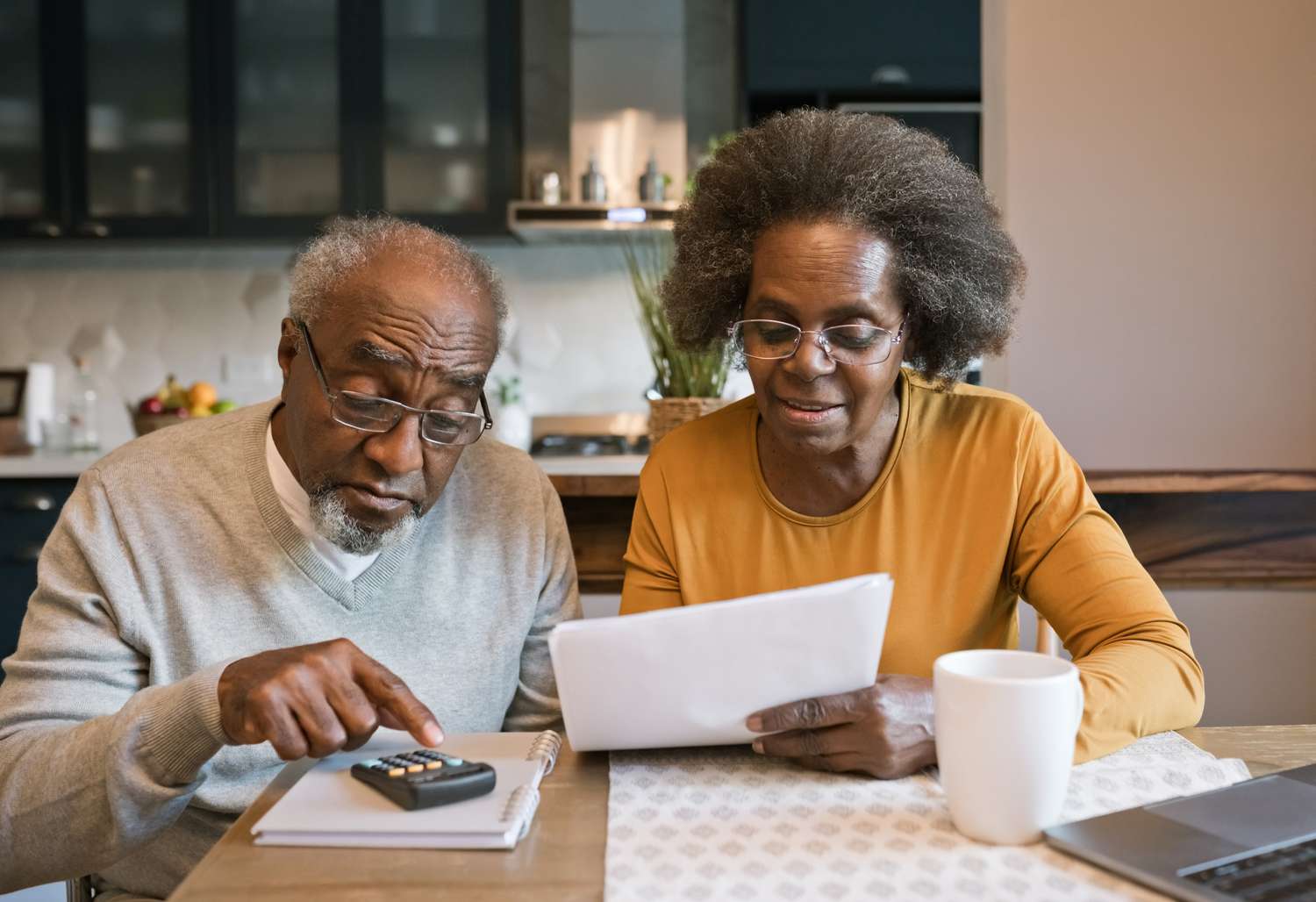 Senior woman and man sitting at the table at home and going through bills.
