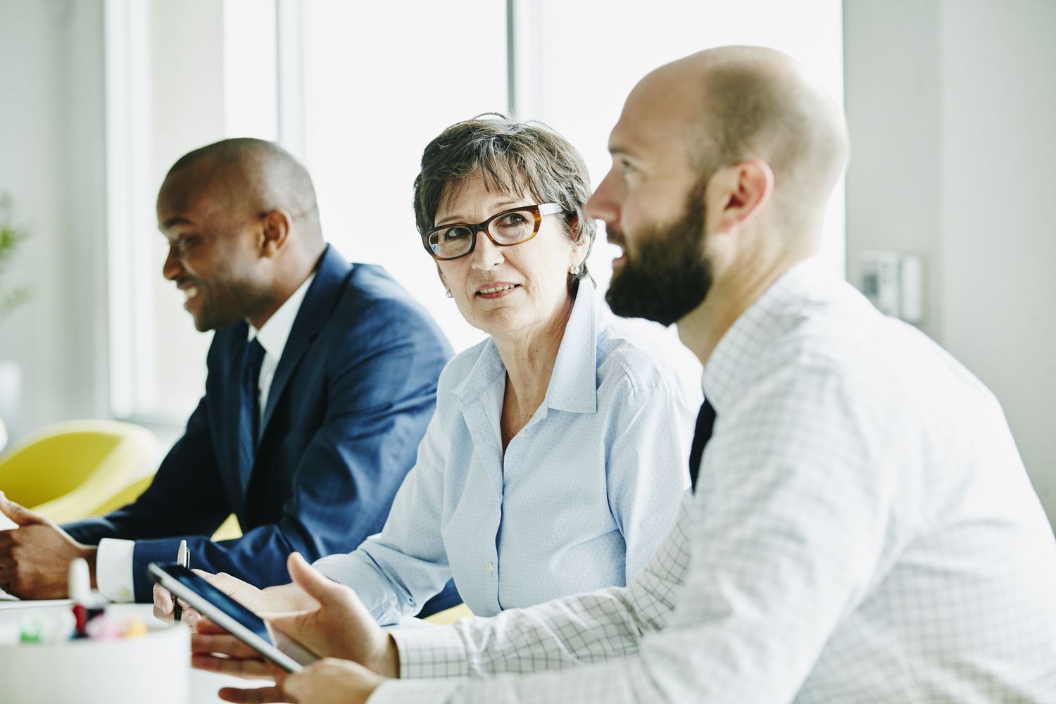 Three executives have a discussion in a boardroom