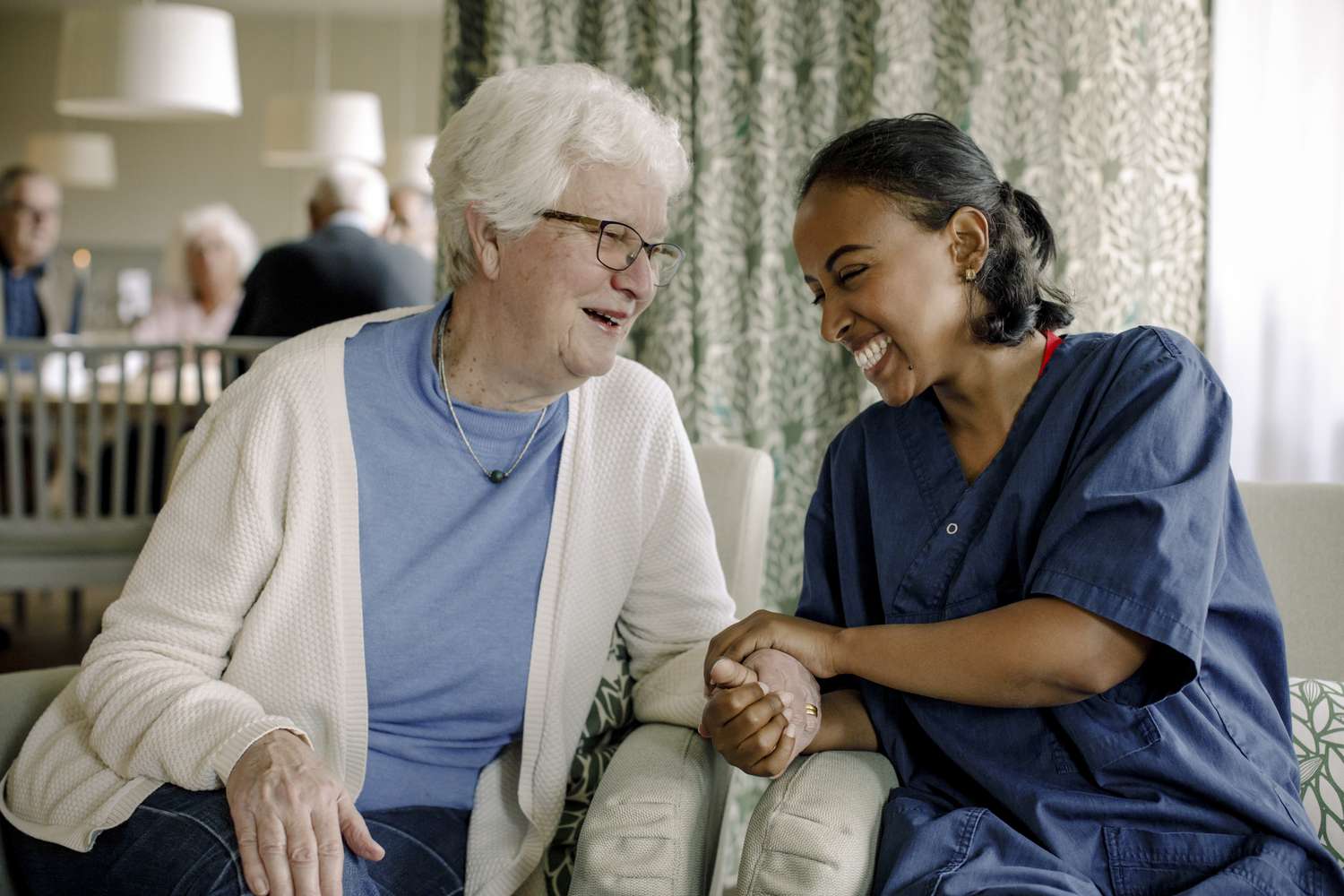 A nurse shares a laugh with a senior woman in a nursing home.