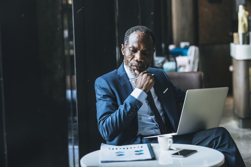 A man with a laptop looking at papers