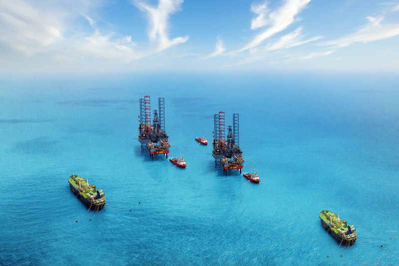 Aerial view of two oil rigs in the ocean surrounded by ships