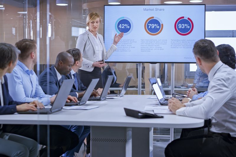 A businesswoman holding a presentation using display in glass conference room.