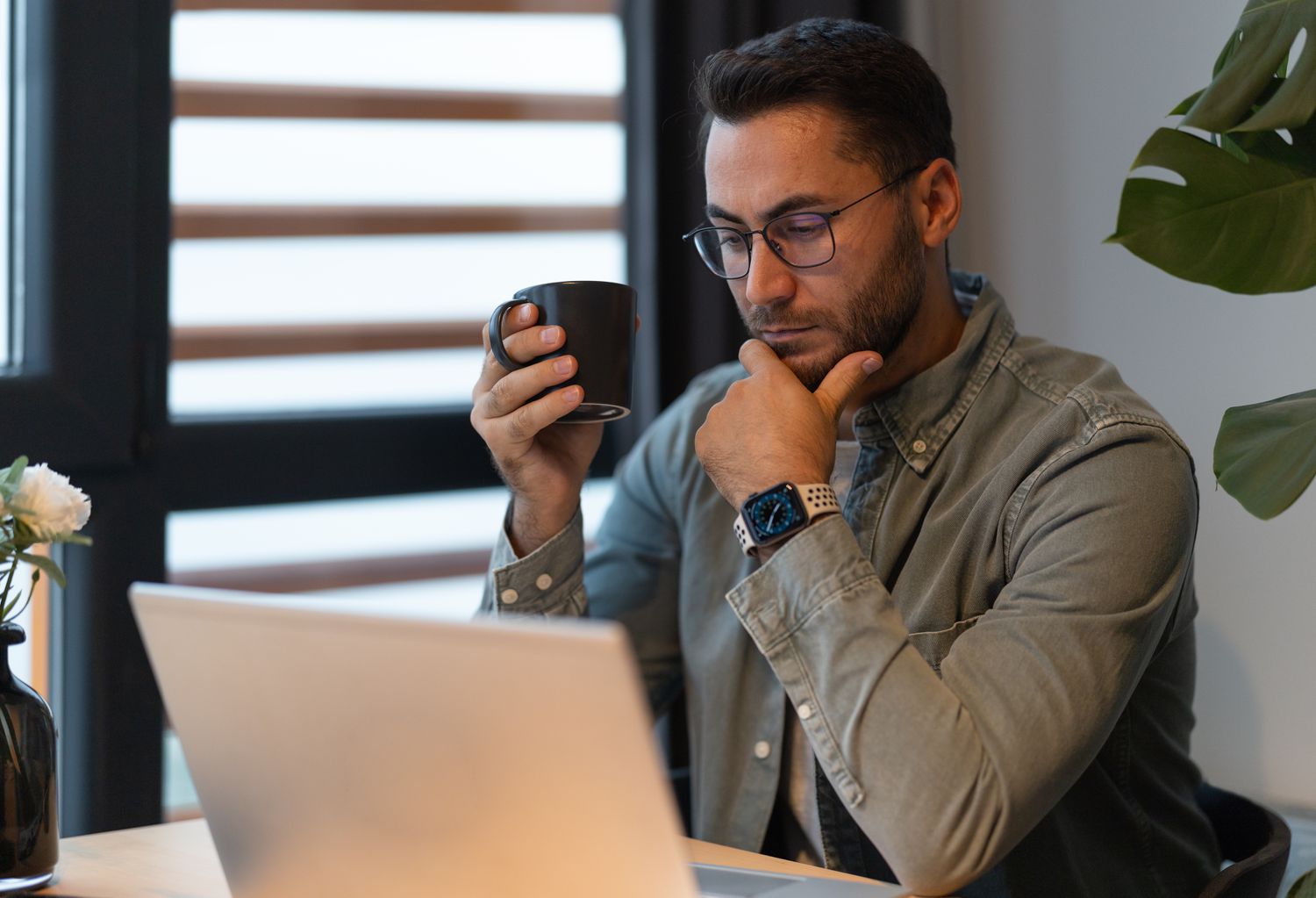 Man in his 30s sitting at home and looking seriously at his laptop