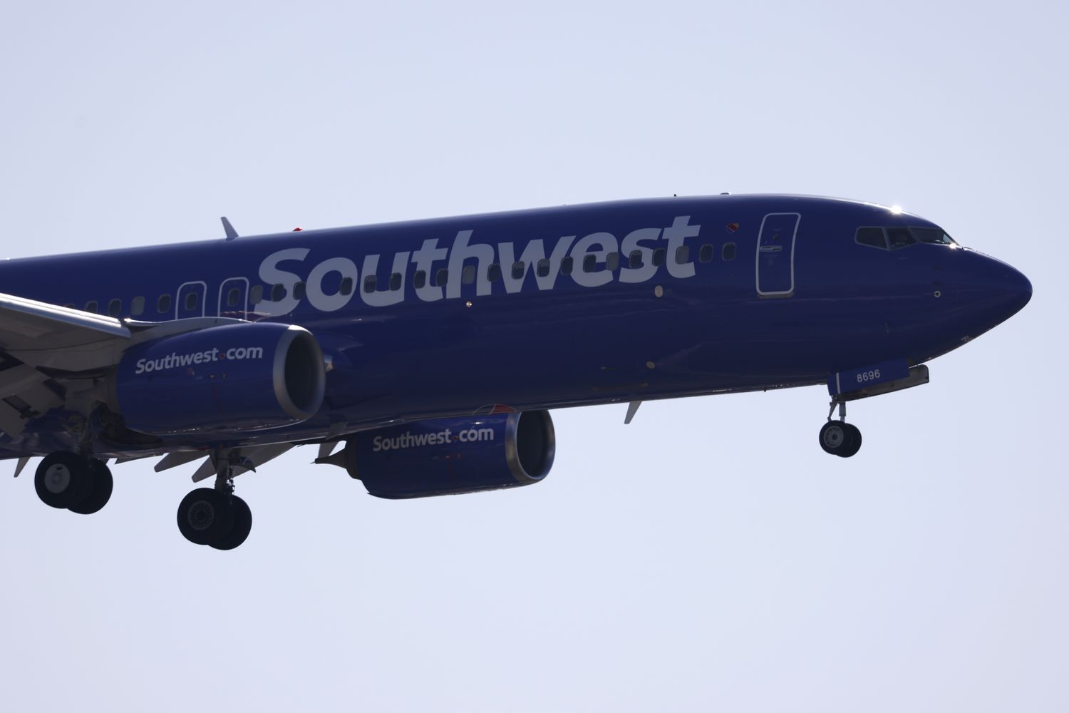 A blue Southwest Airlines plane is seen in the sky with its landing gear extended.