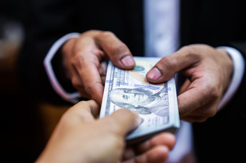 a person handing over a stack of money