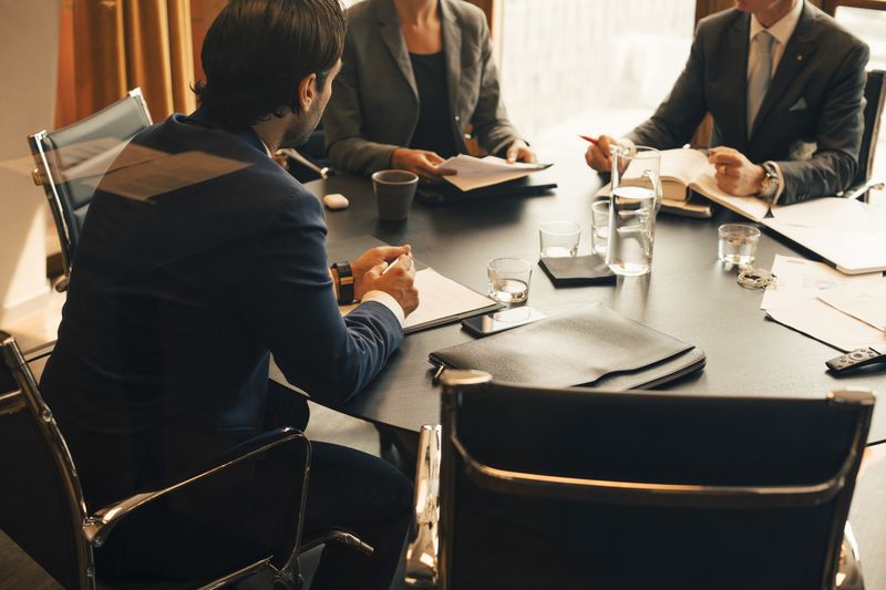 A executive management team meets around a table filled with documents to discuss the need to issue a new class of shares.