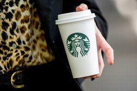 Pedestrian holds a Starbucks cup.