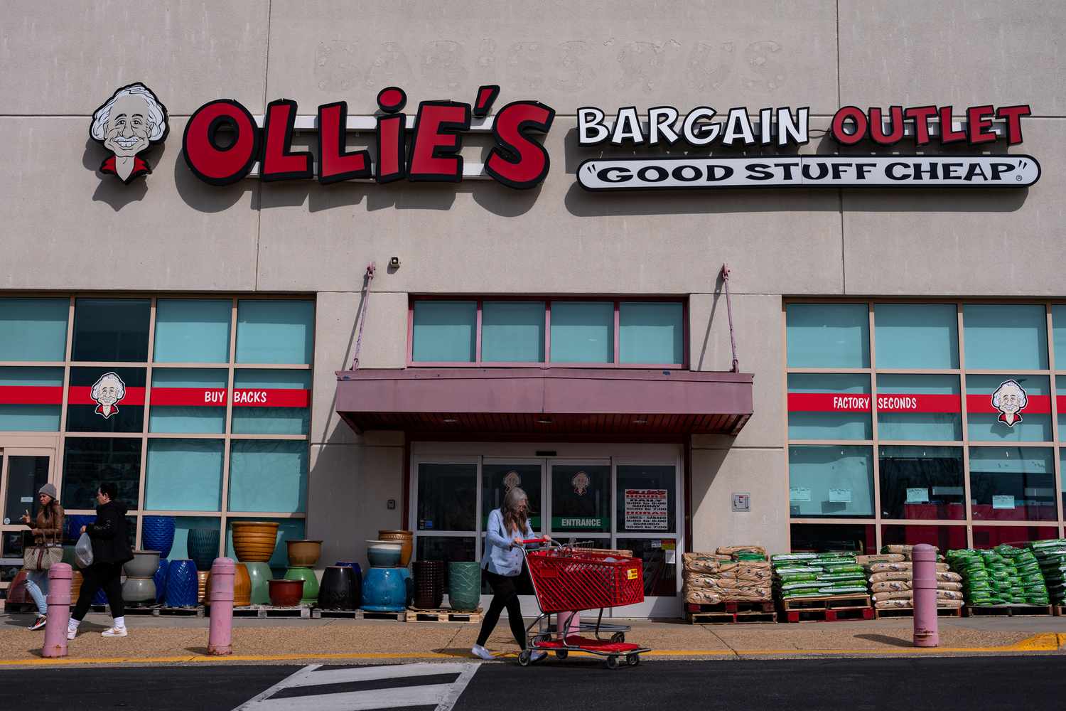 People walk in front of an Ollie's Bargain Outlet store.
