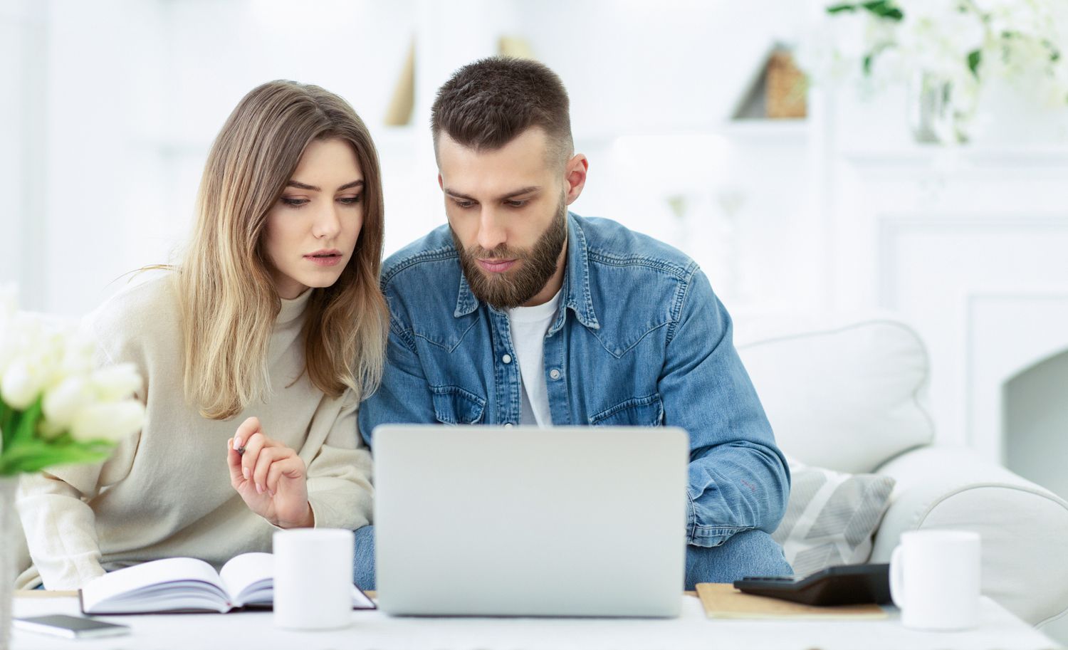 Young couple sitting in their living room and looking together at a laptop