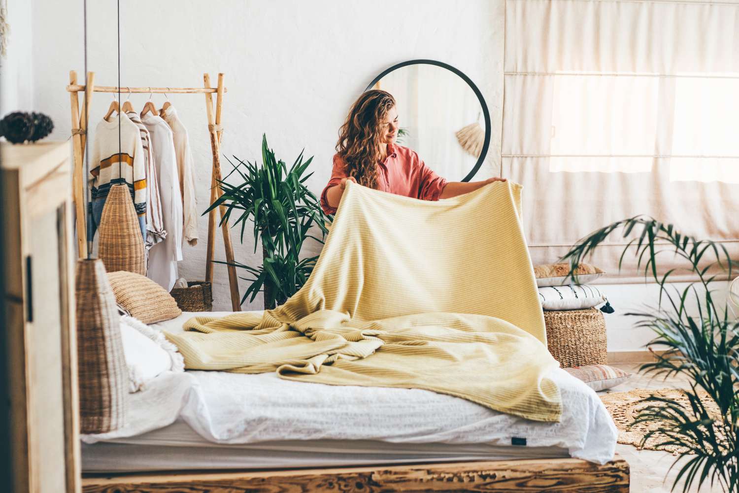 A woman makes a bed with a yellow blanker