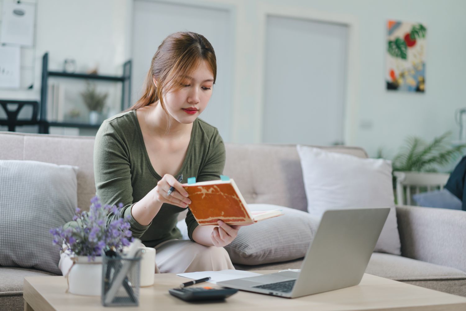 A person sits on a couch with a laptop on a table in front of them.