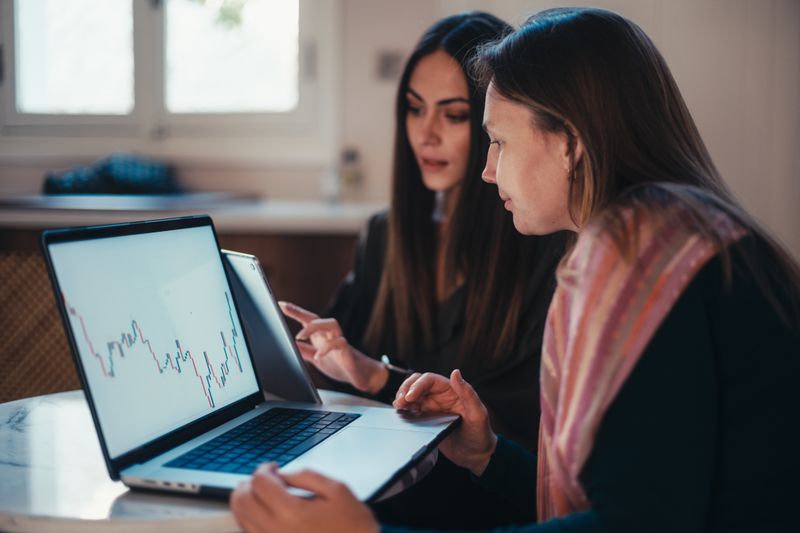 Two women looking at a chart on a laptop