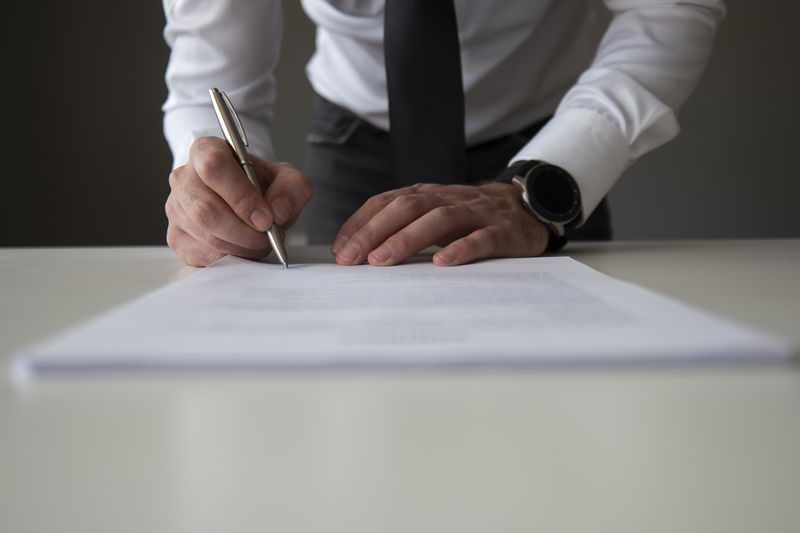 A company CEO uses a pen to sign an SEC form to correct previously stated offering information.